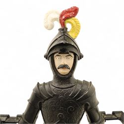 Early 20th century painted cast iron hall stand, formed as a standing armoured figure with red and yellow feathered crest, twin rails and integral drip tray with castellated edge