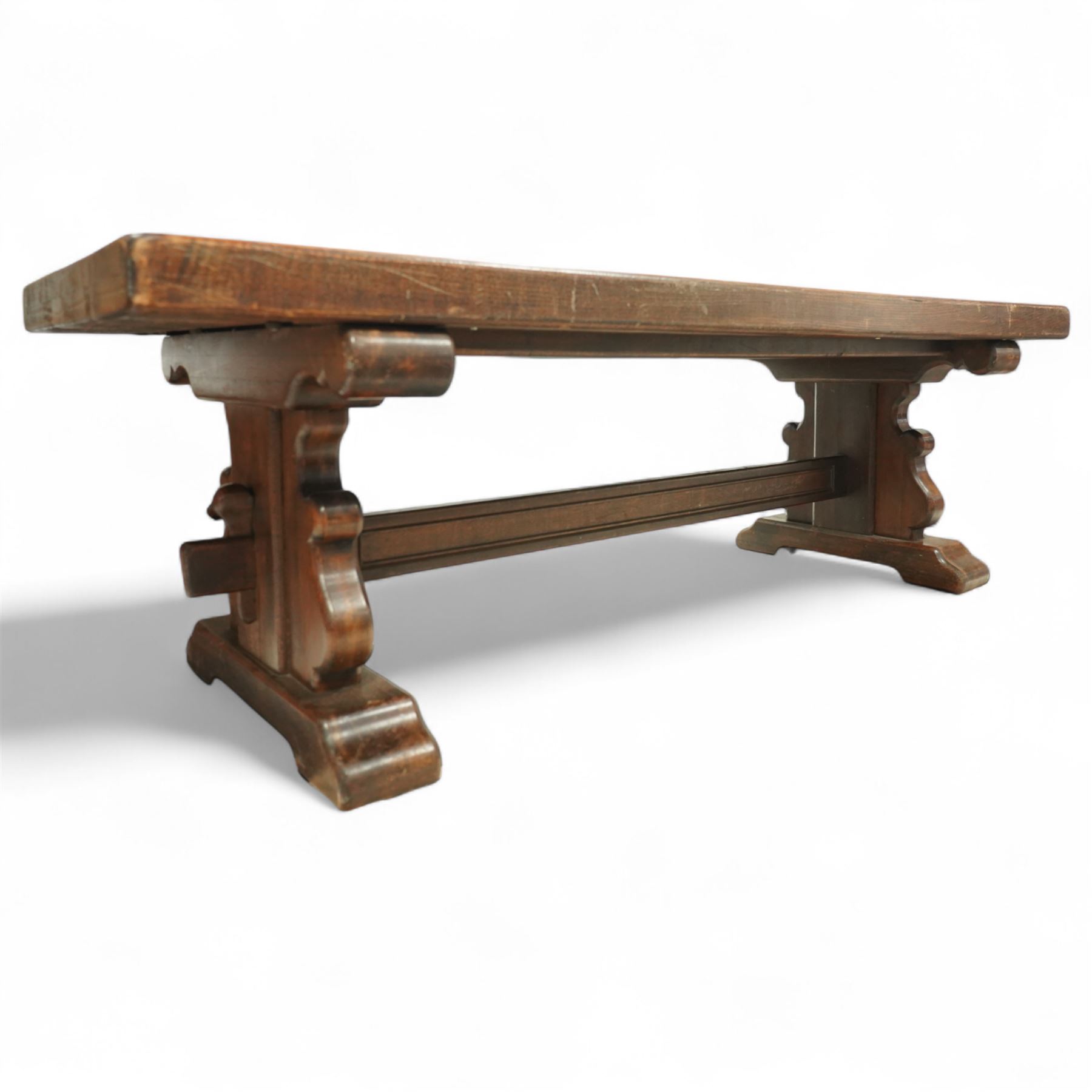 Early 20th century French oak refectory table, the thick rectangular top with cleated ends above shaped lyre-form trestle supports, united by a central stretcher, on broad scrolled feet, displaying well-figured quarter sawn grain across the top