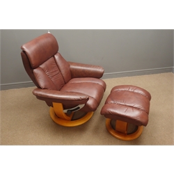  Swivel reclining armchair upholstered in brown leather with matching footstool  