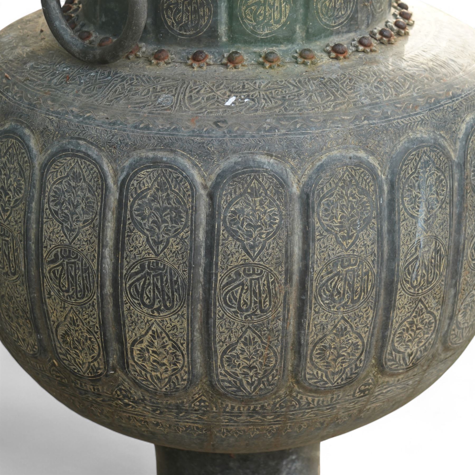 Pair of large Indian cast metal garden urns, each of bulbous form with engraved foliate and script panels, twin ring handles to the neck, raised on fluted pedestal bases