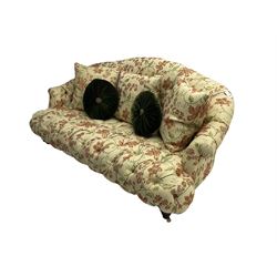 Victorian style three seat sofa, upholstered in beige ground floral floral pattern fabric, with scatter cushions, turned feet with brass castors