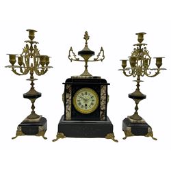 Late 19th century French mantle clock with a Parisian single train eight-day timepiece movement, enamel dial with roman numerals, minute markers and steel moon hands, brass bezel with gilt egg and dart slip, pendulum regulation arbor, Belgium slate case with inlaid panels of contrasting white and black veined marble, incised decoration to the plinth and pediment, grotesque masks to the sides, with a stepped plinth raised on four paw feet, pediment surmounted by a gilt and marble ornamentation on a foliated circular base with crocket finial, pair of candelabras in matching form with four scrolling branches and lights centred by a fifth.
With key and pendulum. 
