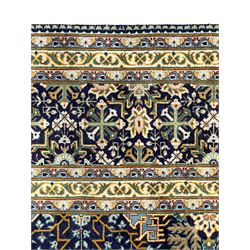 Persian indigo and pale gold ground rug, overall busy geometric design, the field decorated with hooked Hac and palmette medallions surrounded by densely patterned zig-zags and stylised foliate motifs, the border decorated with smaller Hac motifs, within multiple guard stripes 