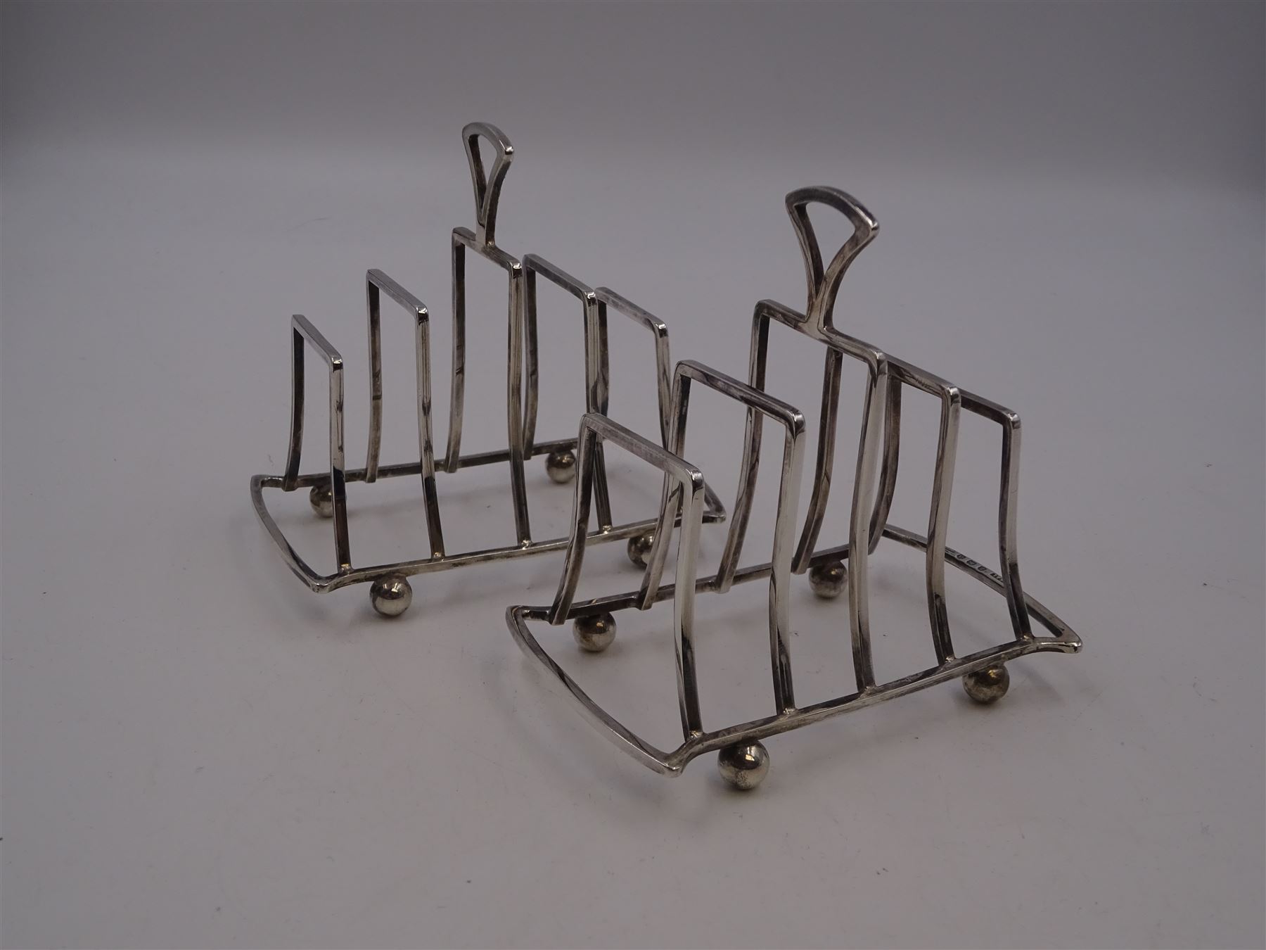 Pair of Art Deco silver five bar toast racks, each of graduating geometric form, with loop handle, upon four bun feet, hallmarked G Unite & Sons & Lyde Ltd, Birmingham 1928, H9cm