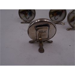 Set of four early 20th century silver mounted place card holders, each of circular form and set with a coloured fly fishing hook behind a glazed panel, upon three pad feet, hallmarked Grey & Co, Chester 1912, H4.5cm, contained within red fitted case, with purple silk and velvet interior