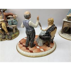 Six Capodimonte figures, comprising the first example modelled as a fisherman with a net on naturalistic rocky base, the second modelled as an elderly gentleman seated at a desk writing in a book with a quill, the third modelled as a watchmaker, another modelled as a seated tramp on a bench, another as a gentleman sat beside a tree stump hammering, and a figure group of a gentleman and lady with a mirror