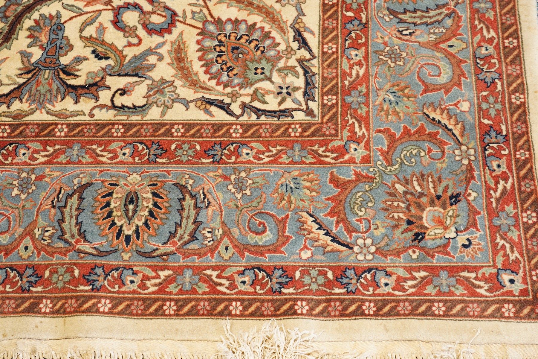 Persian Isfahan ivory and crimson ground rug, the busy field with central floral pole medallion surrounded by foliate motifs and stylised palmettes, the indigo guard line with repeating scrolling plant motifs