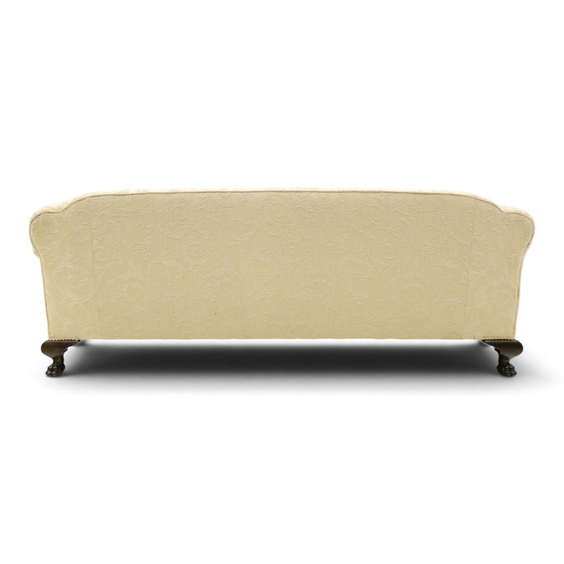 Quality Edwardian carved mahogany lounge suite comprising three-seater settee and pair of armchairs, the sofa with arched back over rolled arms and deep sprung seat, the arm terminals carved with acanthus rosette over gadroon and rope-twist moulding, the shaped apron carved and moulded with scrolling foliate acanthus motifs, terminating to four large front hairy paw and ball feet, upholstered in pale yellow foliate fabric with matching seat and scatter cushions (W200cm D105cm H73cm); the matching deep armchairs (W78cm D95cm H75cm)