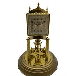 A “Kundo” 400-day torsion clock made by the 20th century German manufacturer Kieninger & Obergfell, with a  decorative square dial and pierced steel hands within a foliate bezel, on a circular base with adjustable feet, four-ball rotary pendulum under a glass shade. 
H30cm
