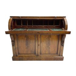 Victorian mahogany roll-top writing desk, top concealing fitted interior with pigeonholes and three drawers, the trisector inset writing surface with writing slope, base fitted with panelled cupboard enclosing single shelf, decorated with scrolled corbels