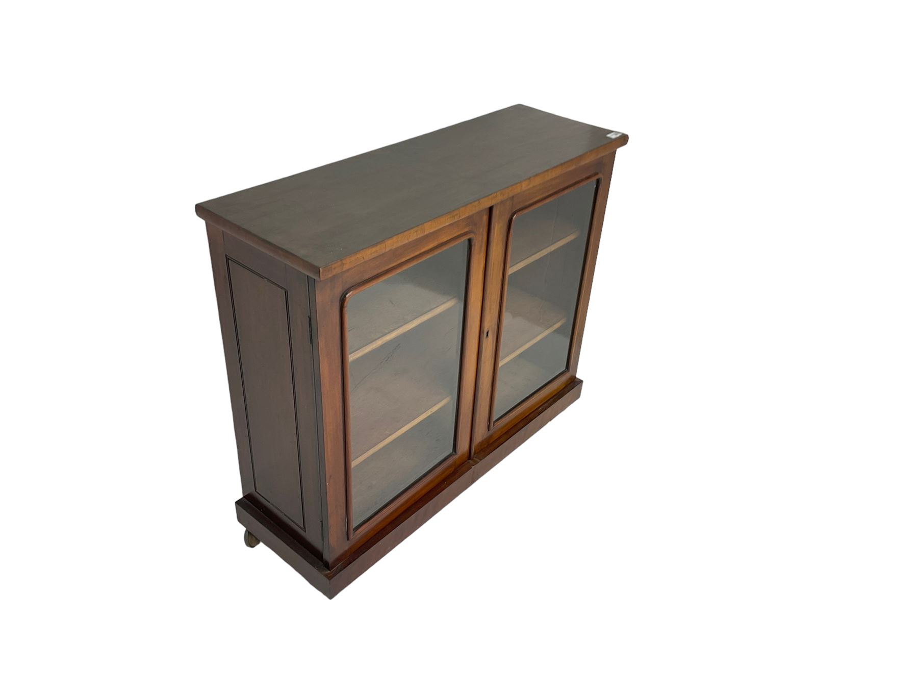 Victorian bookcase, rectangular top over two glazed doors enclosing two shelves, on skirted base