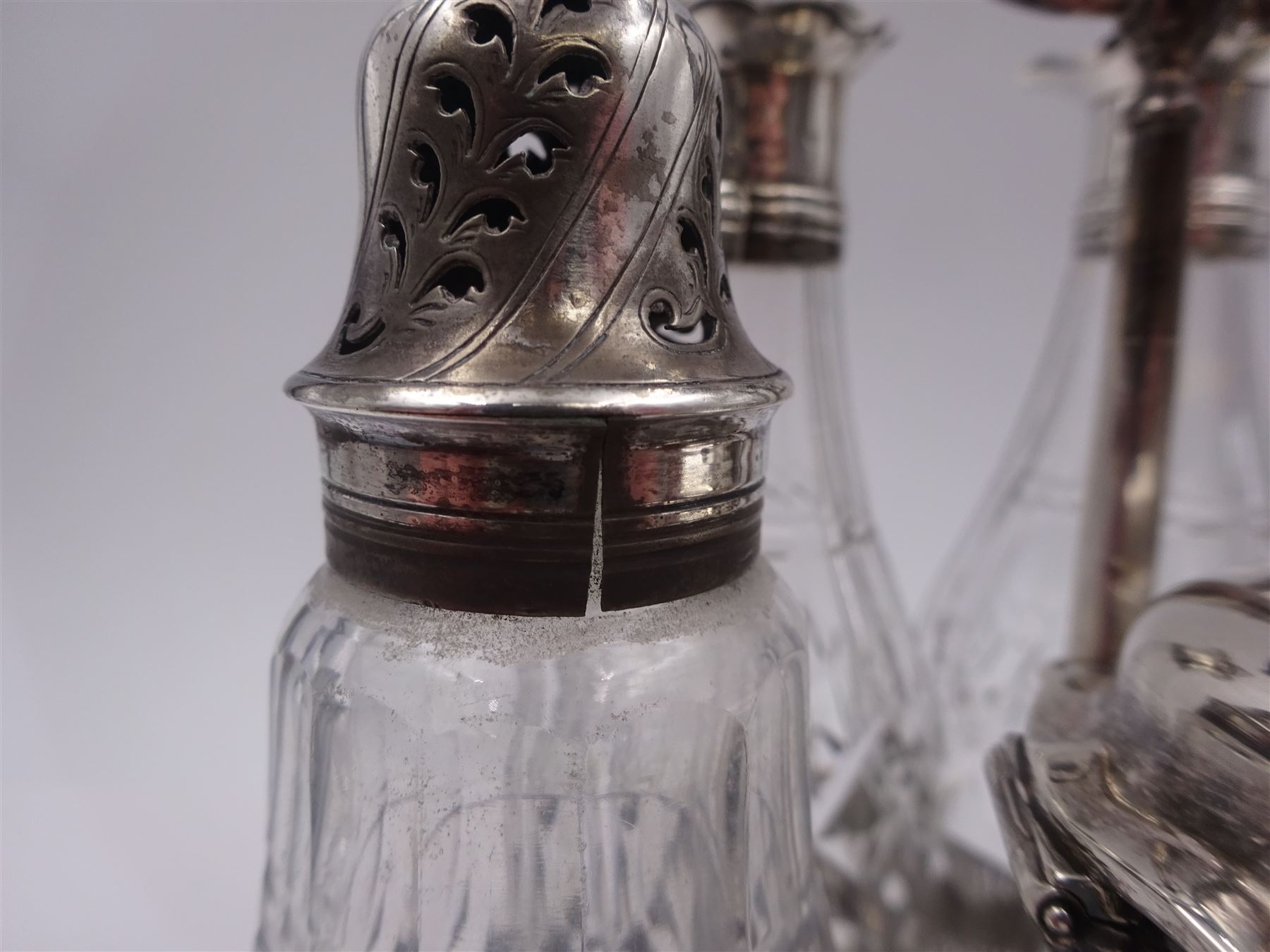Late 18th century silver cruet stand, of oval form, with pierced sides upon four bun feet, hallmarked to handle Hester Bateman, all other hallmarks indistinct, together with five matched silver mounted cut glass cruet bottles, including some later Victorian examples, hallmarks predominantly indistinct, stand H20cm