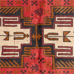 Turkish Anatolian rug, crimson ground, with stepped geometric medallions in ivory, brown, and black within angular striped borders in tones of red and ochre 