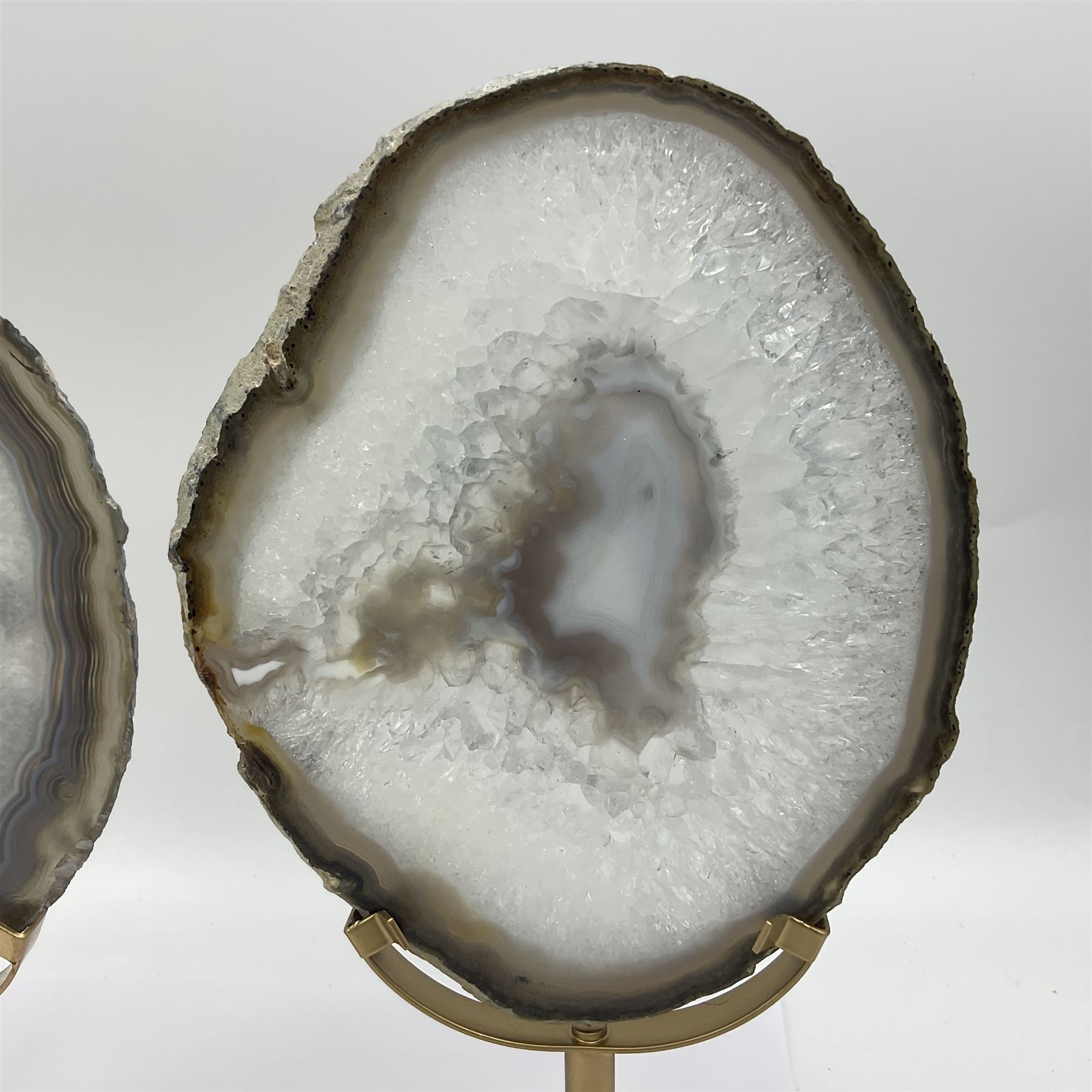 Pair of white agate slices, polished with rough edges raised upon gilt metal stands, H24cm