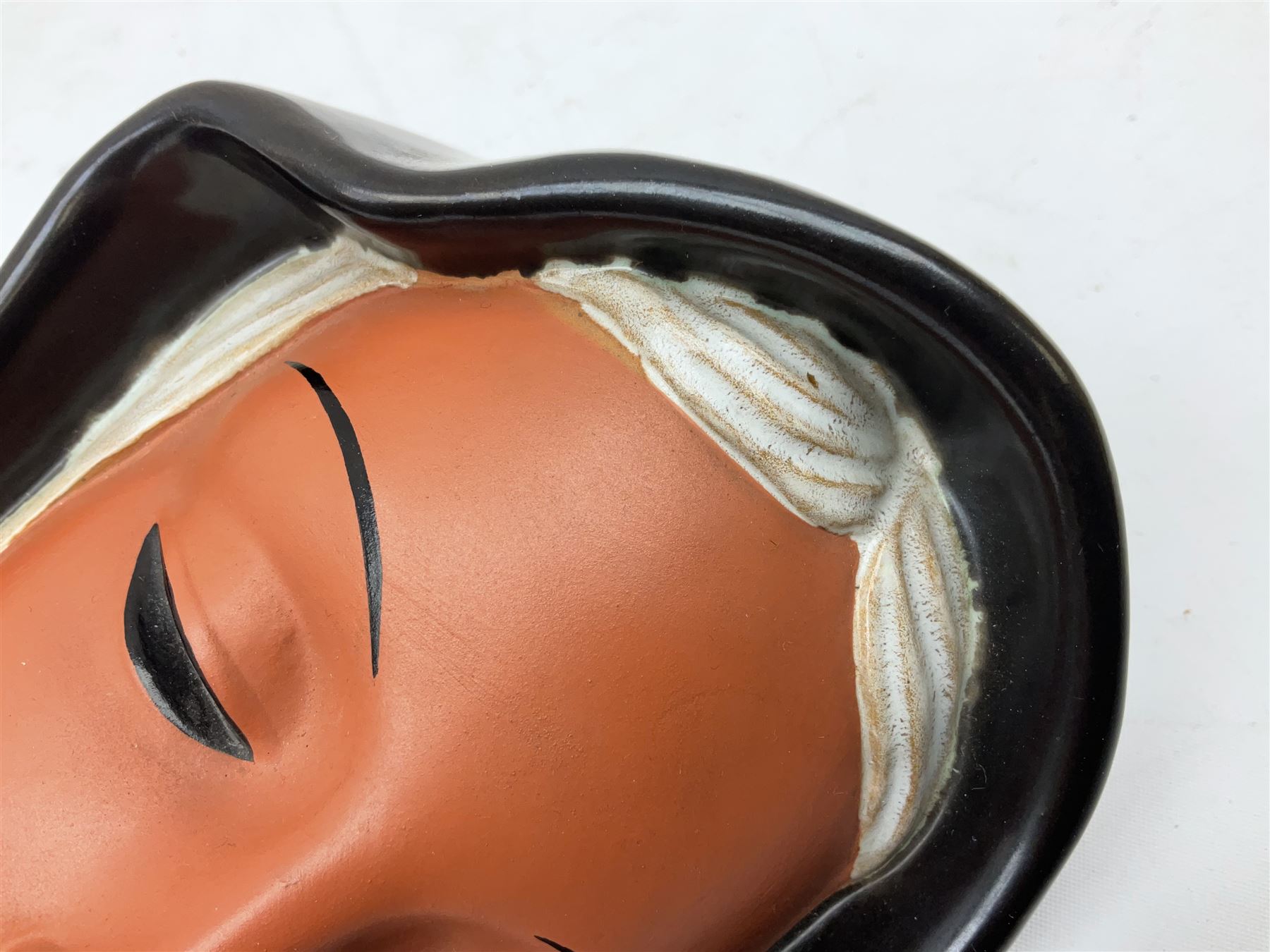 Art Deco Goldscheider terracotta wall mask, modelled as a woman in a black headscarf, model no 7831, with printed mark to back, H20cm 