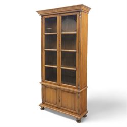 Pair of late 20th century Thai hardwood display cabinets, each with moulded cornice over twin glazed doors enclosing adjustable shelves, panelled cupboard doors below flanked by fluted columns, raised on bun feet