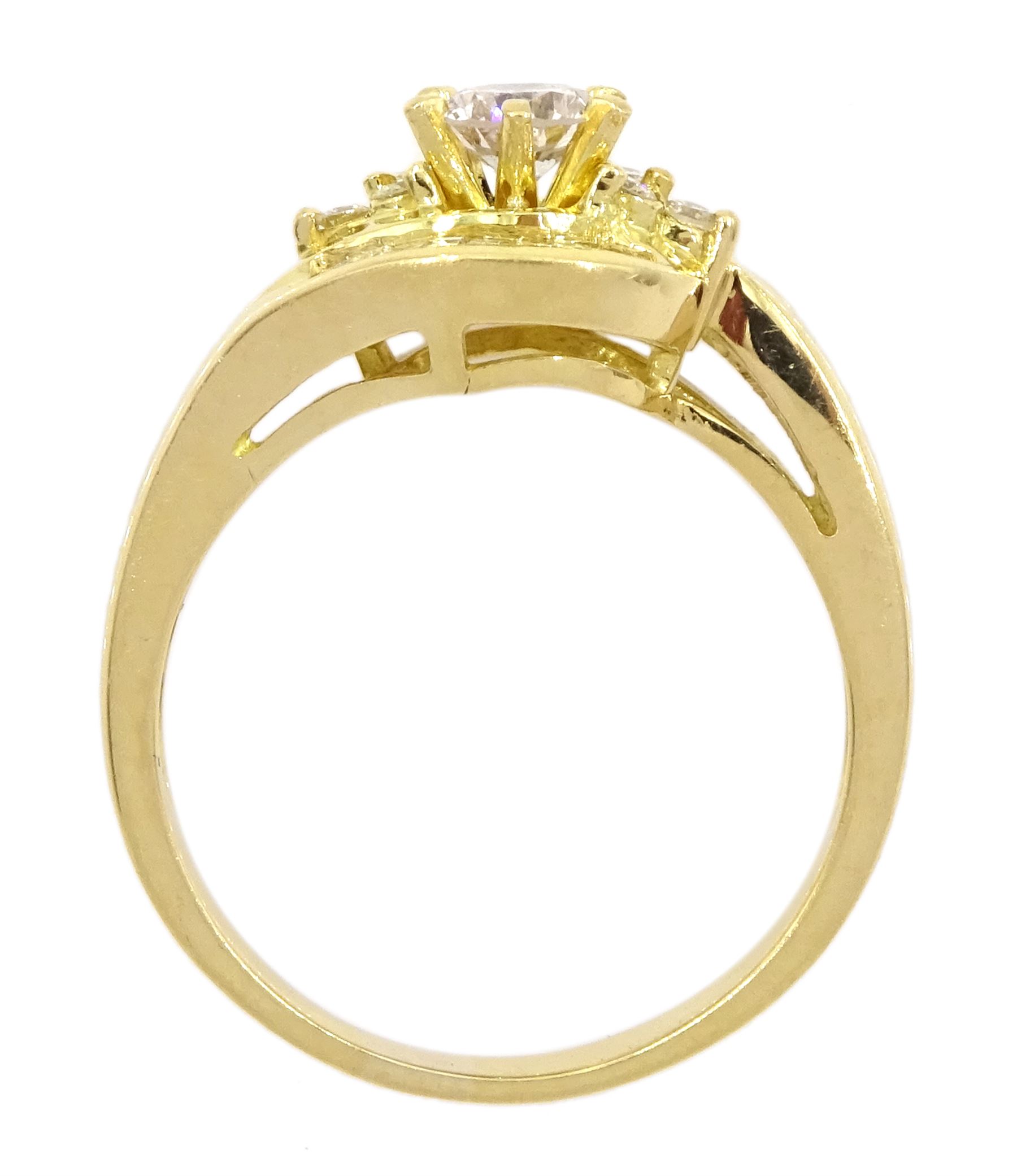 18ct gold diamond crossover ring, the central round brilliant cut diamond of approx 0.45 carat, with round brilliant and tapered baguette cut diamond surround, total diamond weight approx 1.00 carat