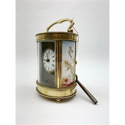 Late 20th Century brass cased carriage time piece clock, oval form set with circular Roman dial and painted enamel panels at each side, arched carrying handle, with key