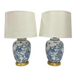 Pair of Chinese porcelain blue and white lamps in the form of ginger jars and covers, each decorated with landscape scene, raised upon gilt circular base, including shade H63cm