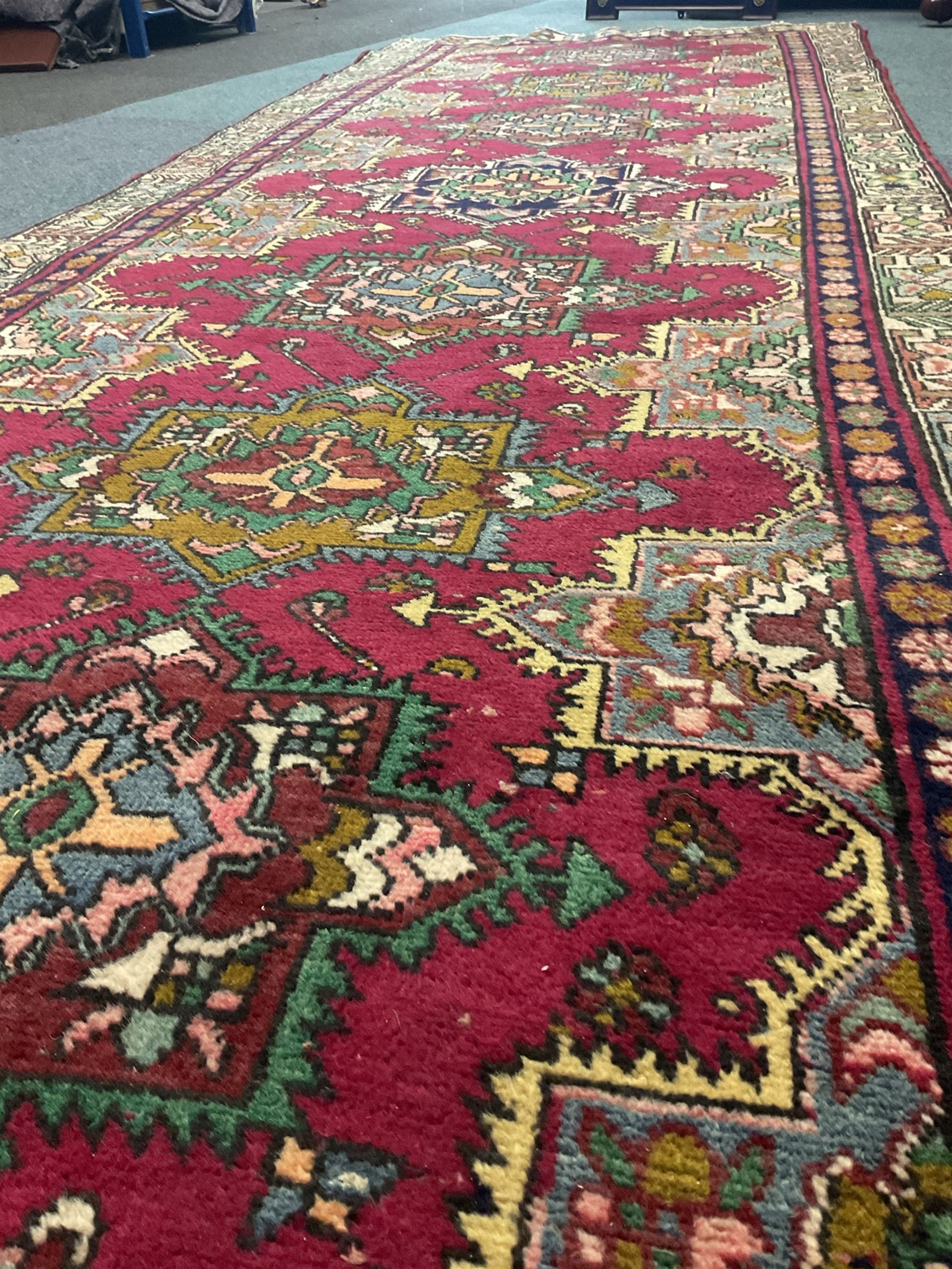 Persian red ground rug, repeating patterned spine in multicolour
