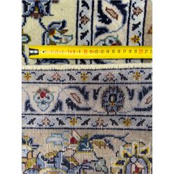 Central Persian Kashan hand-knotted carpet, ivory field with an all-over design of scrolling vines, lotus palmettes, and rosettes in shades of blue, gold, and brown within a blue ground border of palmettes and arabesques between multiple guard stripes