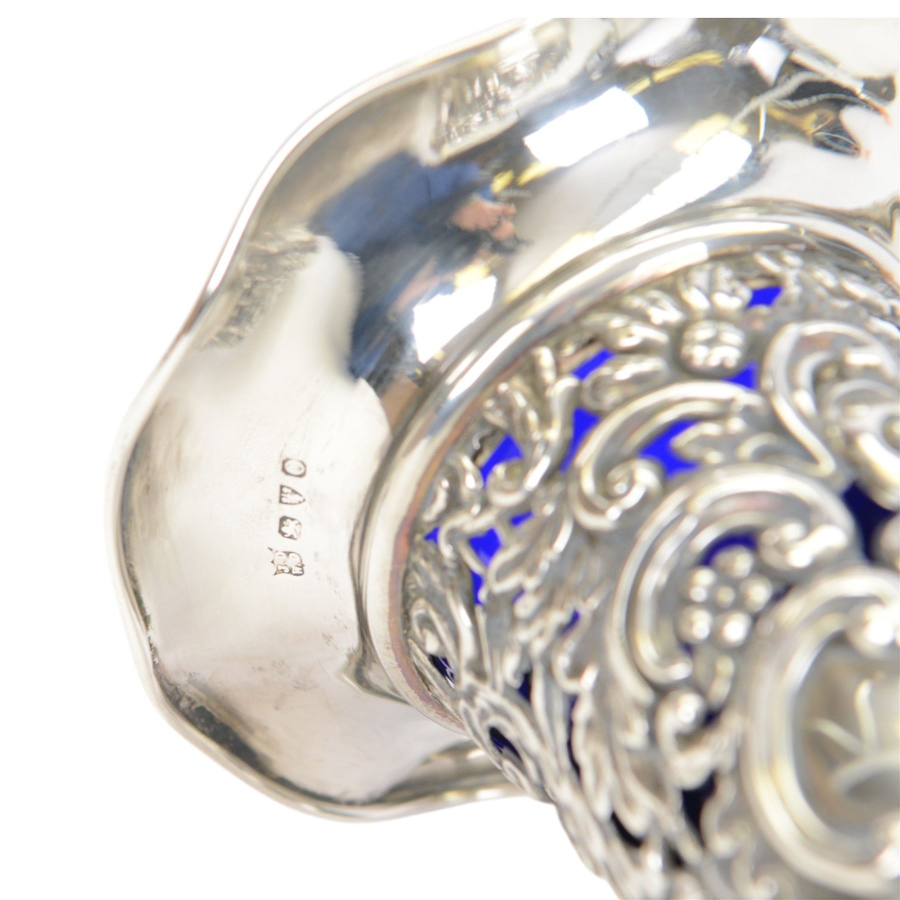 Two late Victorian silver mounted vases, including blue glass mounted example with fluted rim and upon circular foot, hallmarked Henry Matthews, Chester 1900 and a tapering example with fluted rim and pierced embossed scroll decoration to body, with blue glass liner, hallmarked James Deakin & Sons, Chester 1897, tallest H18.5cm