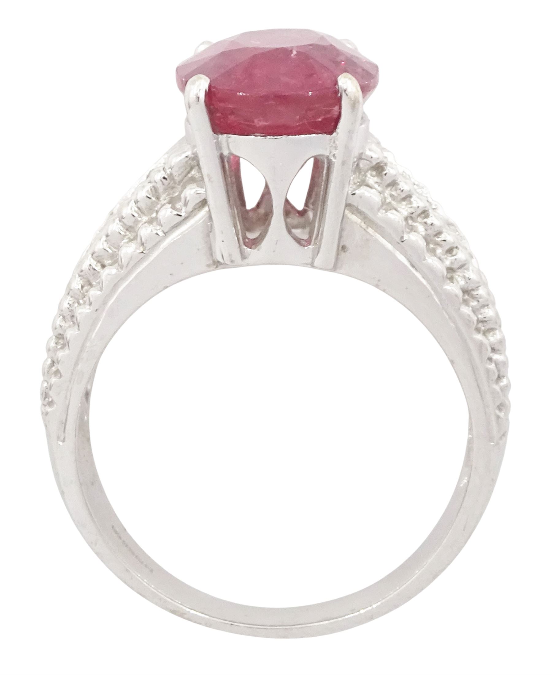 18ct white gold ruby and diamond ring, single oval cut ruby of approx 5.05 carat, with three round brilliant cut diamonds to each shoulder, Birmingham 2006