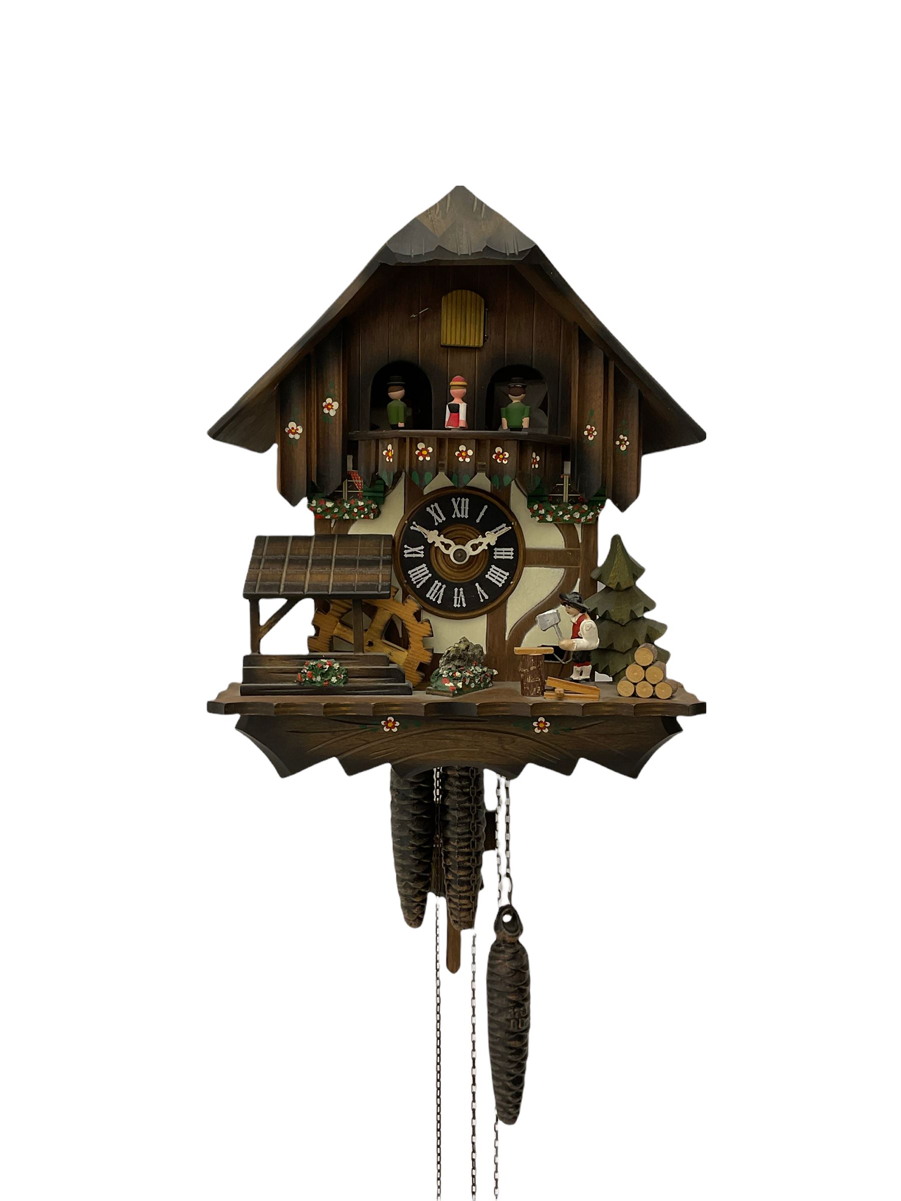 A 20th century West German 30-hour Automaton musical cuckoo clock with a Swiss musical movement playing three tunes, visible pendulum and three cast metal pine cone weights, carved pine wood case with automaton water wheel, woodsman and carousel, chapter ring with Roman numerals and decorative hands, with strike/silence lever.

