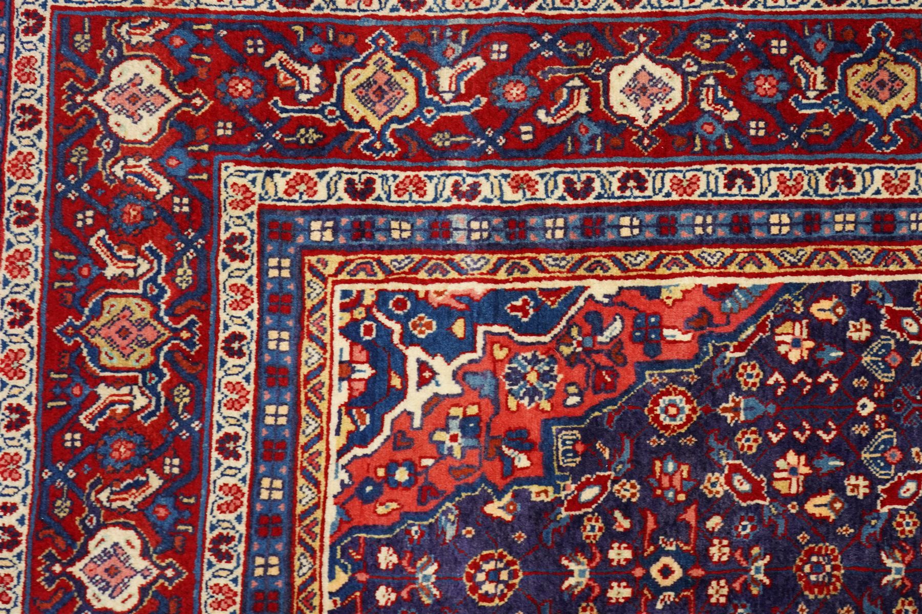 West Persian Mahal hand-knotted carpet, indigo field with central stylized angular medallion issuing an all-over Herati-inspired lattice of floral sprays, rosettes and geometric vinery in tone soft madder red, ivory and soft blue, principal border decorated with stylized palmettes, and angular vine motifs, flanked by multiple guard borders, with cotton fringe ends 