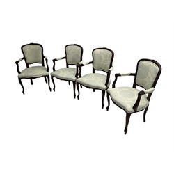 Set four French style stained beech elbow chairs, the cresting rails carved with flower heads, mould arms with scrolled terminals, upholstered in white ground fabric with blue foliate pattern, floral carved cabriole supports