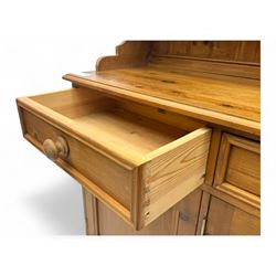 Traditional vintage pine kitchen dresser with scrolled cornice and rack with long shelf above a galleried shelf flanked by three short drawers and two cupboards, the base with three long drawers above three cupboards on plinth base  