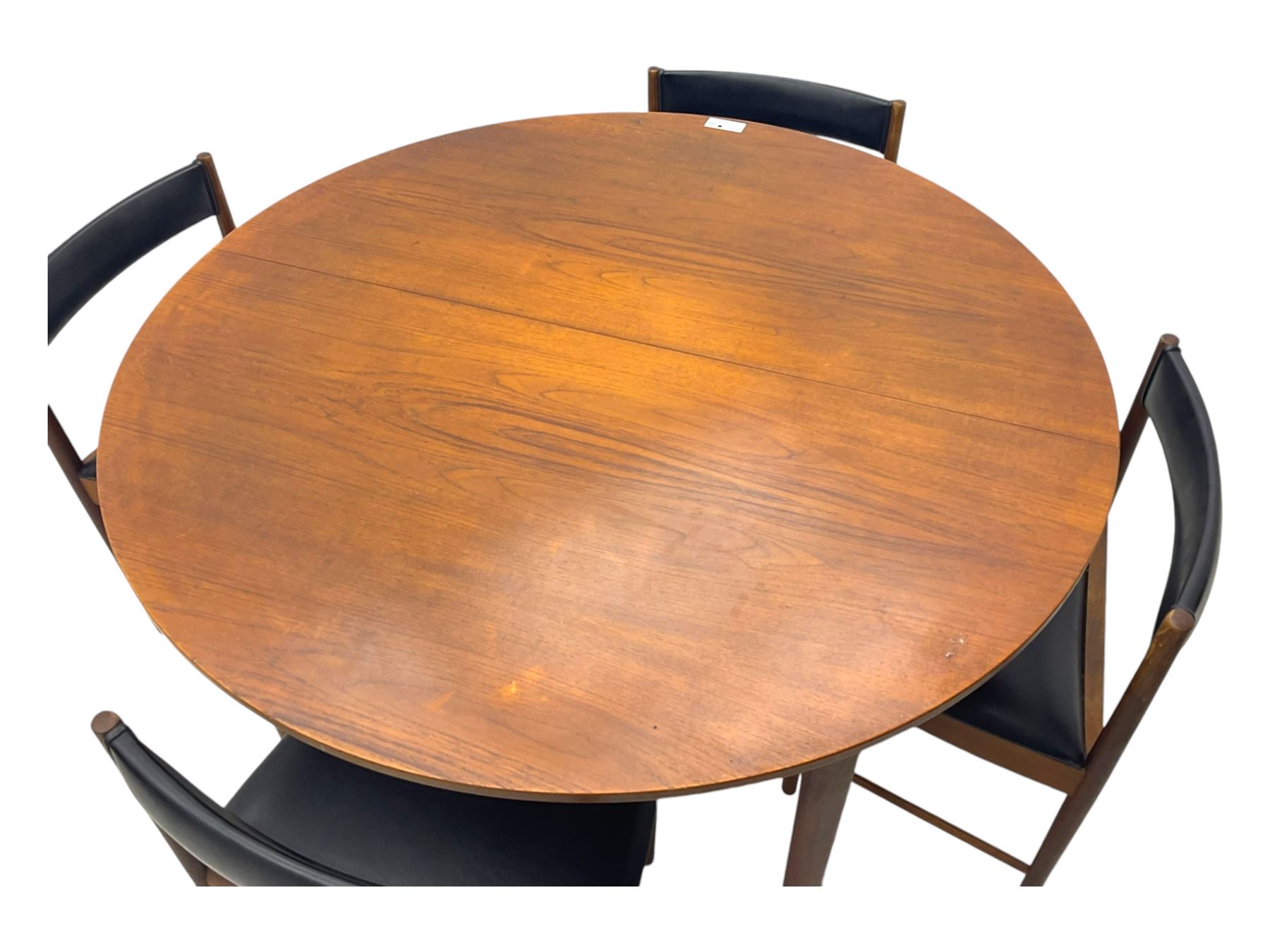 Mid-20th century teak extending dining table, circular top with pull-out extension and concealed leaf extension mechanism, on tapered supports; set of four teak dining chairs with black vinyl padded seats 