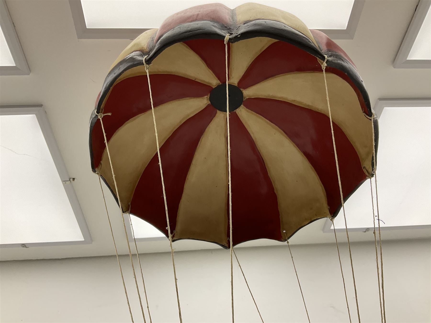 Painted wooden hanging model of a hot air balloon group, the balloon above a wicker basket complete with sandbags and figures, together with a similar example with a clown figure below, H68cm