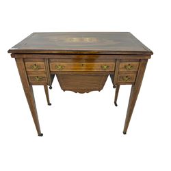 Edwardian inlaid mahogany games or work table, rectangular fold-over top inlaid with stylised dragon ivorine decoration and stringing, fitted with one long flanked by four small drawers over sewing compartment drawer, raised on square tapering supports with castors
