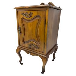 Edwardian Art Nouveau walnut bedside cabinet, raised broken swan neck back with carved flower heads, single fielded panelled door enclosing single shelf, raised on cabriole supports with ceramic castors
