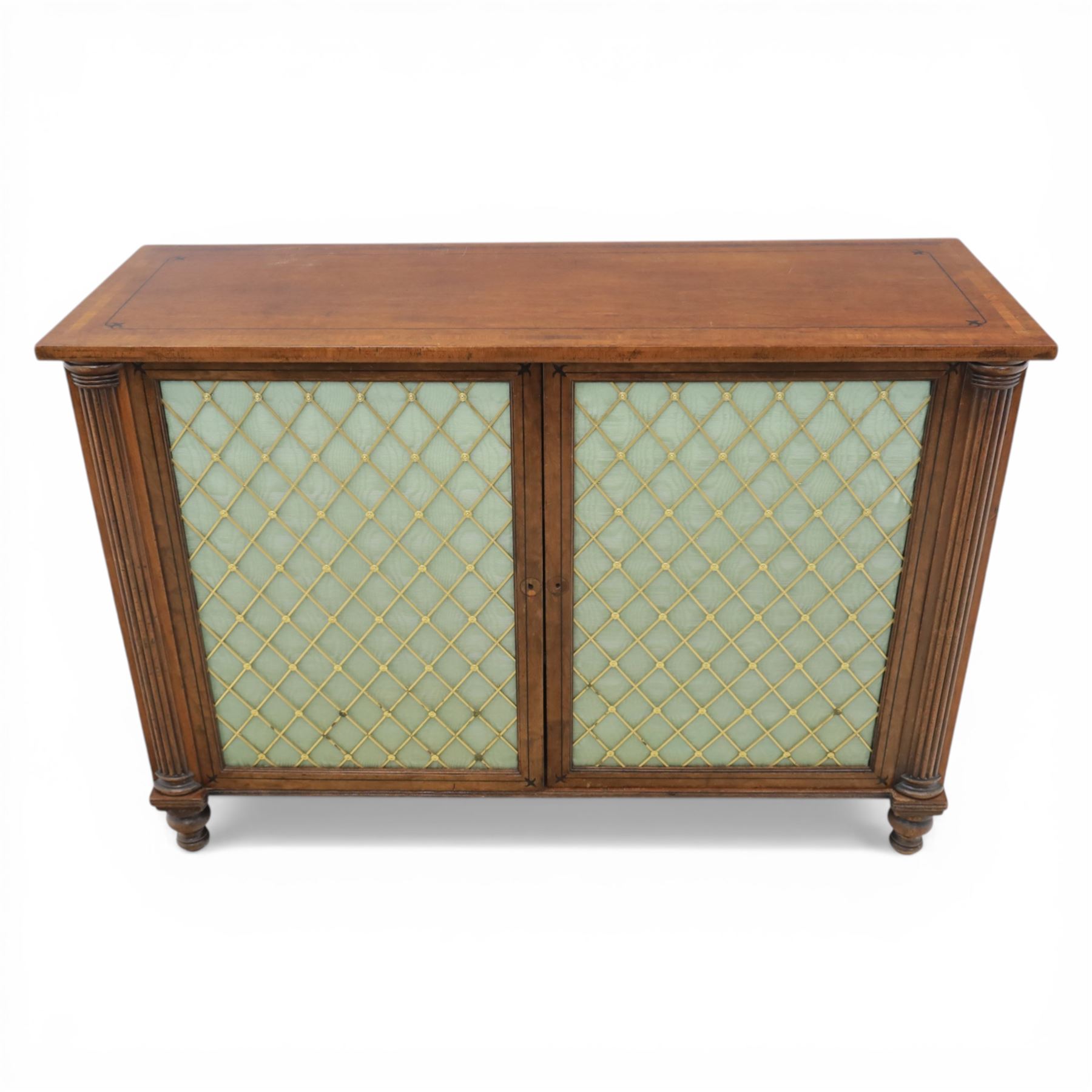 Late 20th century Regency style mahogany side cabinet, the rectangular crossbanded top with ebonised line inlay, above a pair of brass lattice grille doors with pale green fabric backing enclosing a shelved interior and two frieze drawers, flanked by reeded corner pilasters, upon turned tapering feet