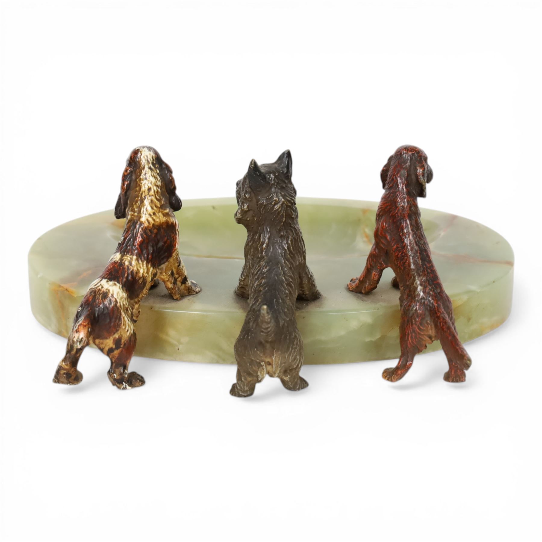Art Deco ashtray, the oval green onyx tray with oval dished recess, the edge surmounted with three cold painted bronze dogs, comprising Irish Setter, Scottish Terrier and Springer Spaniel, each marked with incised H to base of foot, tray L17cm