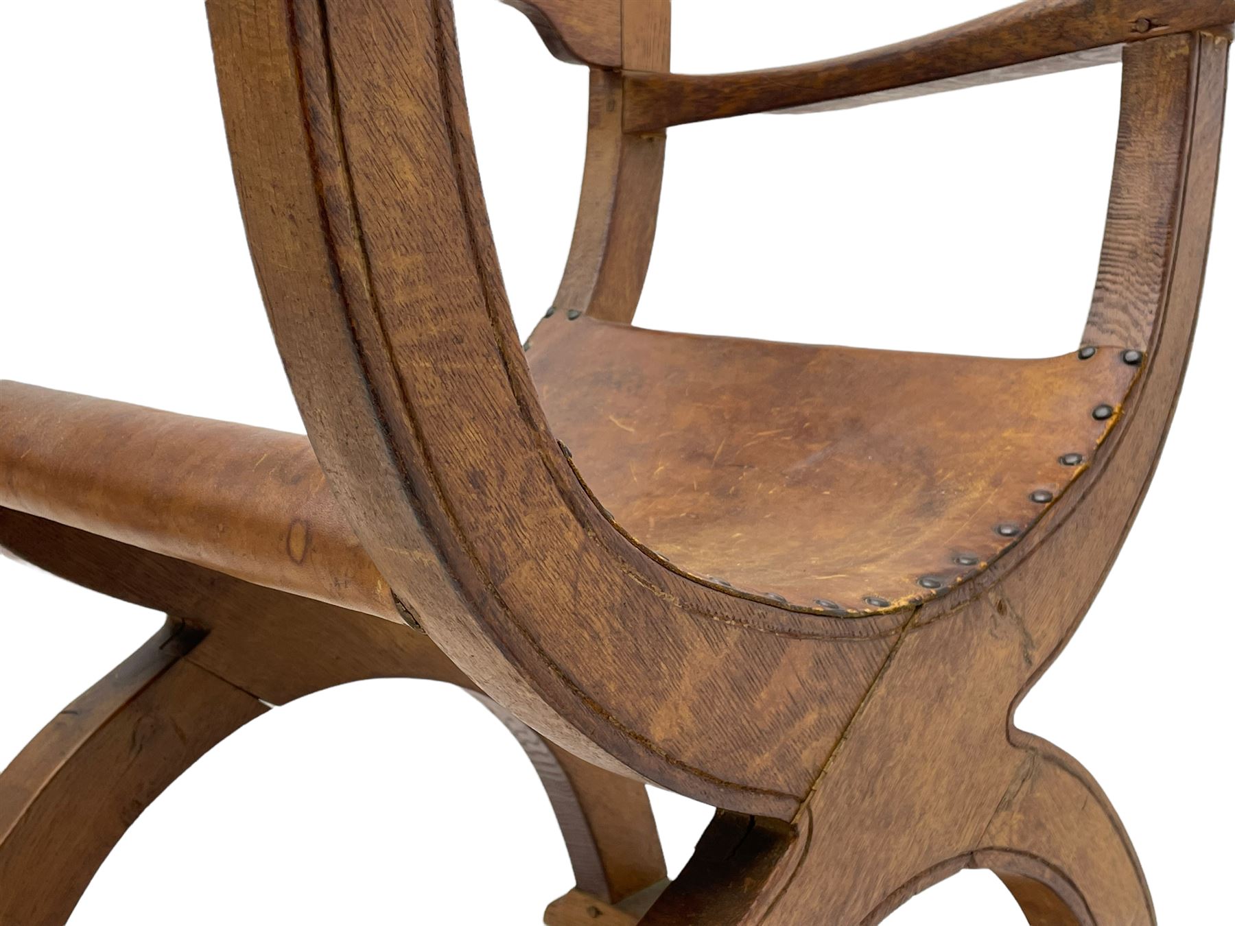 'Gnomeman' oak curved x-framed throne chair, sloped arched cresting rail carved with arcade, studded slung leather seat, the supports joined by sledge feet, rear upright carved with gnome signature, by Thomas Whittaker of Littlebeck