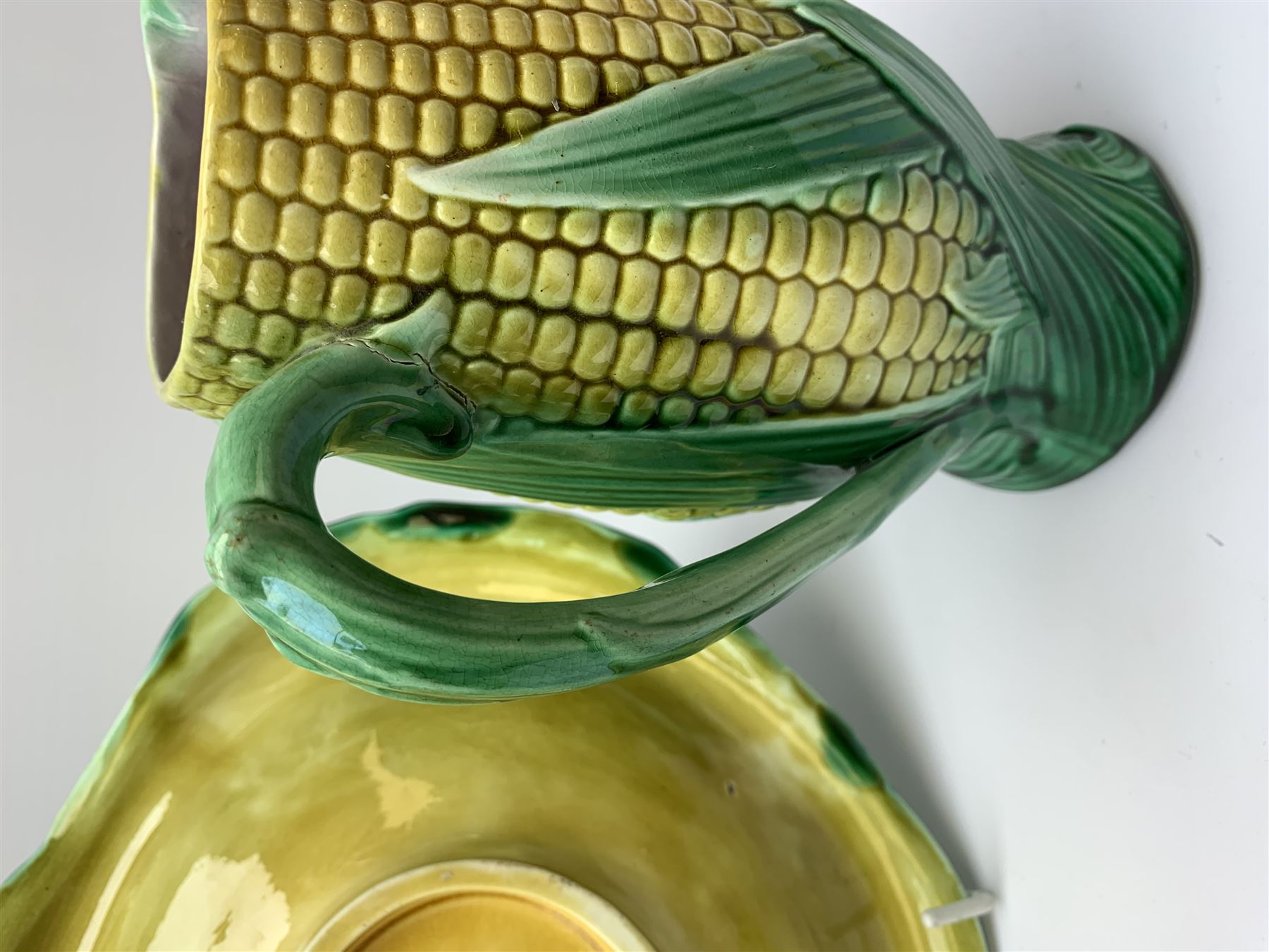 A Victorian majolica bread plate depicting corn within a woven basket, L33cm, together with a Victorian majolica jug modelled in the form of a corn cob, with registration mark beneath, H22cm. 