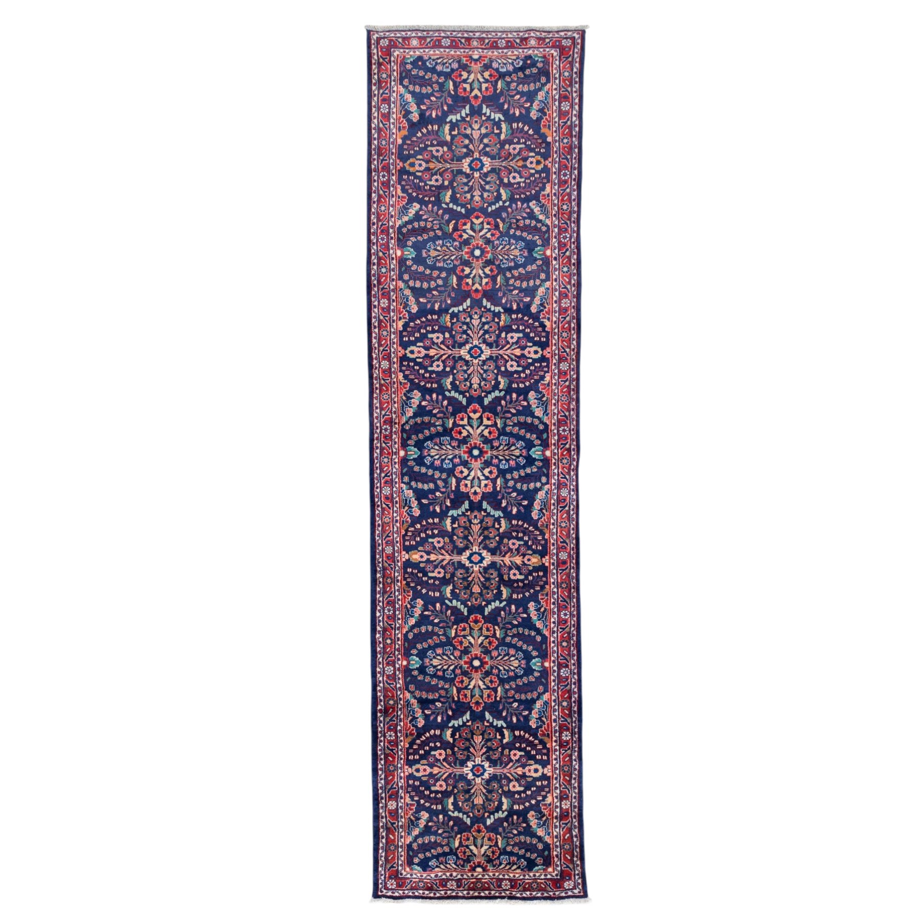 North West Persian runner, the indigo field decorated with repeating symmetrical floral sprays, rosettes and curling foliage in coral, ivory and pale blue tones, enclosed by a red ground trailing flowerhead border and narrow patterned guard bands 