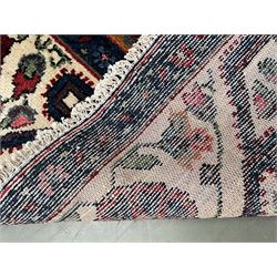 Persian Hamadan rug, the red ground field decorated with two floral medallions and stylised flower heads, repeating guarded border