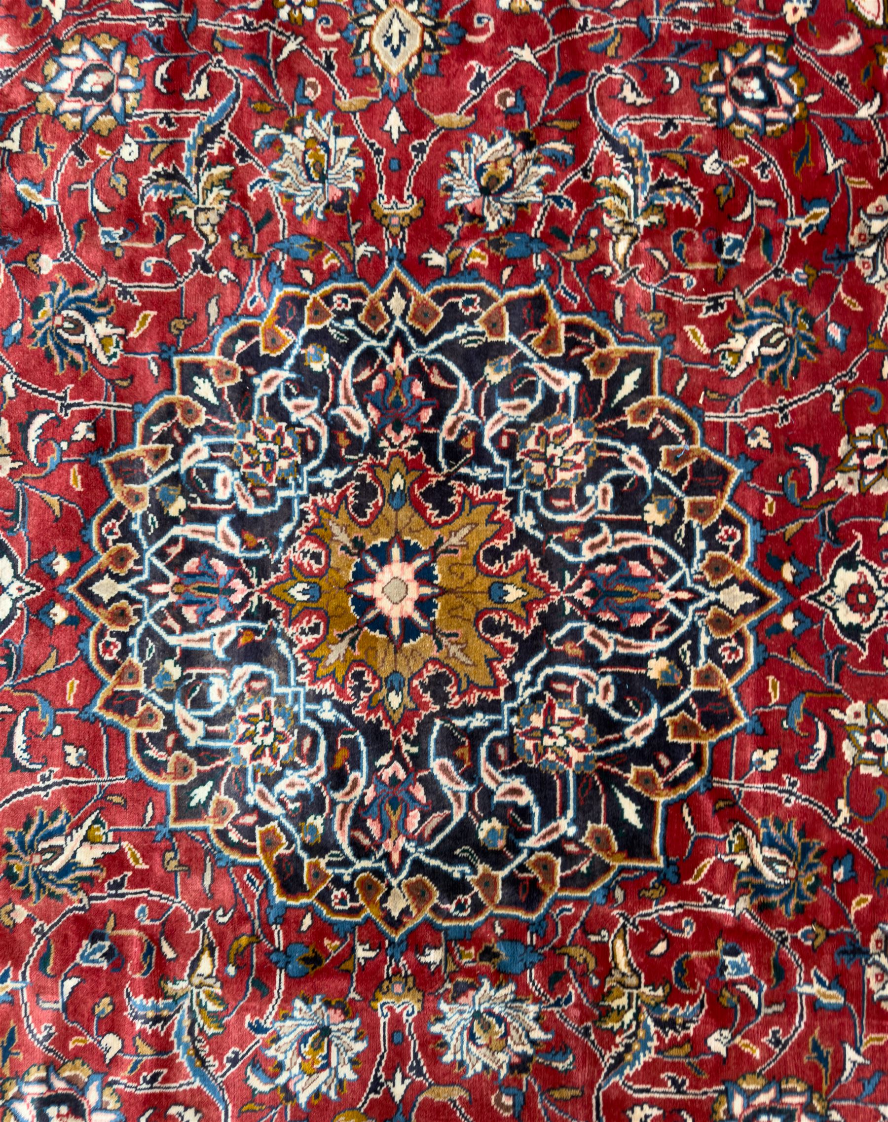 Northwestern Persian Lillihan hand-knotted carpet, madder red field with scrolling vines, rosettes, and palmettes around a central circular medallion in navy, ivory and ochre, and ivory ground spandrels within a navy border of stylized flowerheads and vines between multiple guard stripes 