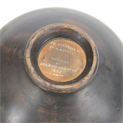 Etruscan terracotta oil lamp, with black glaze, flat loop handle and laurel leaf border, the opening with later turned wooden collar, signed to base 'repaired by one James Naysmith 1887', H7cm 