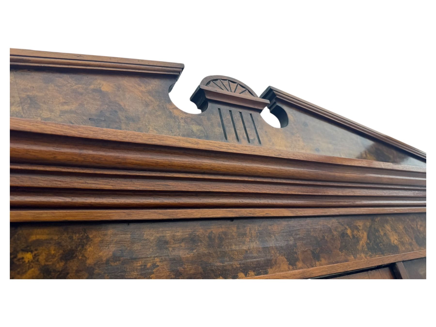 Victorian walnut bedroom suite - wardrobe, dressing chest and bedside cupboard, comprising a full-length wardrobe with broken pediment and central mirrored door, large lower drawer, a matching dressing table with bevelled swing mirror over two trinket drawers and two short drawers over two long drawers, and a single-door bedside cupboard, all with moulded edges, decorative panel work and shaped aprons