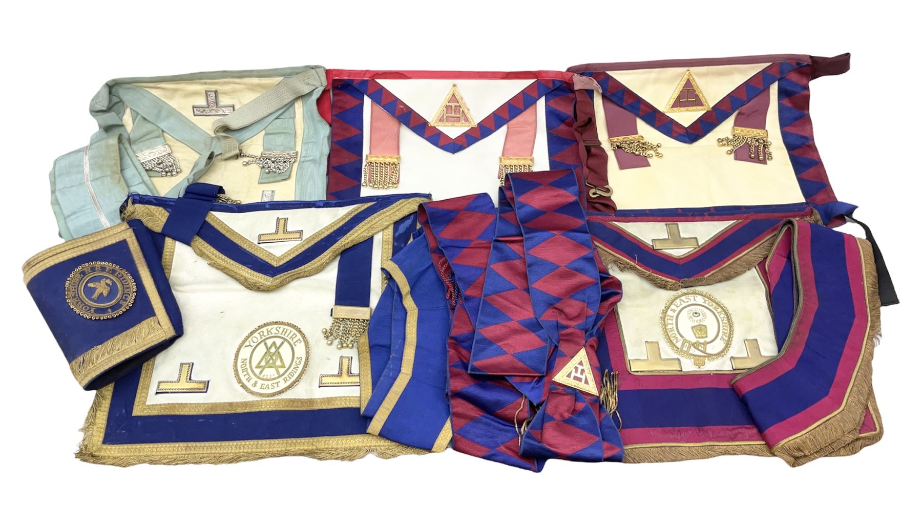 Two Masonic kid leather aprons, one with sash and cuffs, the other with sash, each marked 'Yorkshire North and East Ridings'; and three other unmarked Masonic aprons with sashes