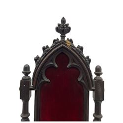 Victorian oak and wrought metal Gothic open armchair, the pointed arched back carved with foliate, cusped inner arch upholstered in red, spiral turned uprights and supports, with arms made of spiral forged metal