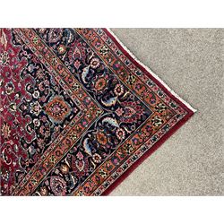 Persian Meshed carpet, plum ground and decorated with stylised flower heads and interlacing foliate, large central stylised medallion with orange detail, the orange mirrored in the five band border decorated with scrolling floral design, signature panel to end 