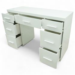 Contemporary white and glass twin pedestal dressing table and two matching bedside chests, dressing table with rectangular top above seven flush-front drawers arranged around a central kneehole, with white matching pulls, bedside chests each with square top over three drawers with integrated handles, plain sides and plinth bases

Bedside tables (W 121cm D 41cm H 82cm)
Dressing table (W 45cm D 45cm H 66cm)