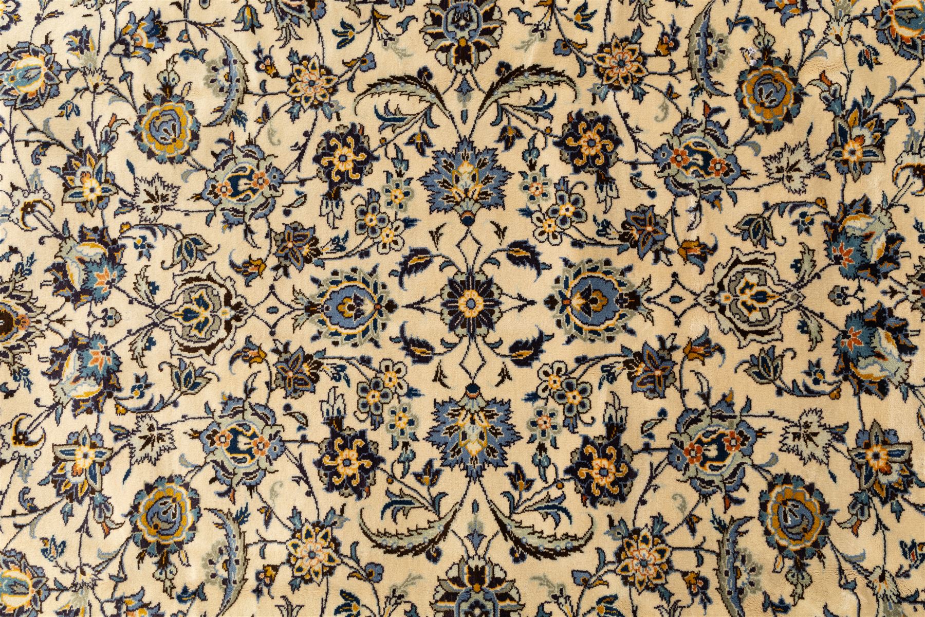 Central Persian Kashan hand-knotted rug, ivory field intricately decorated with an all-over design of scrolling vines, palmettes, and stylized lotus motifs in shades of soft blue, pale gold, and indigo within floral borders