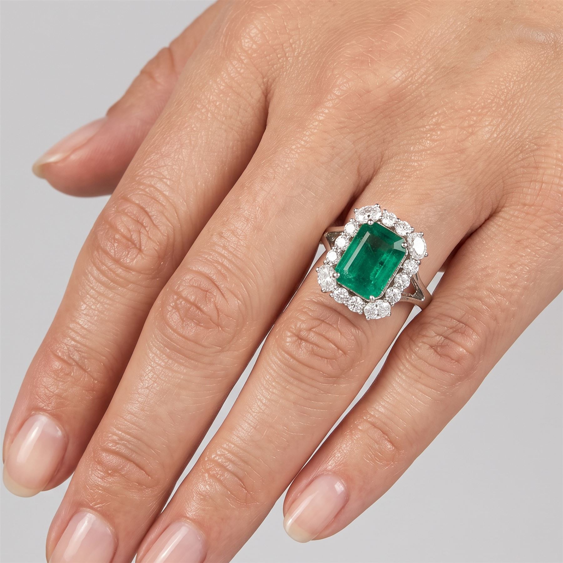 18ct white gold emerald and diamond cluster ring, single octagonal cut emerald of approx 2.90 carat, surrounded by twelve round brilliant cut diamonds and four oval cut diamonds to each corner, stamped 18K, total diamond weight approx 0.90 carat